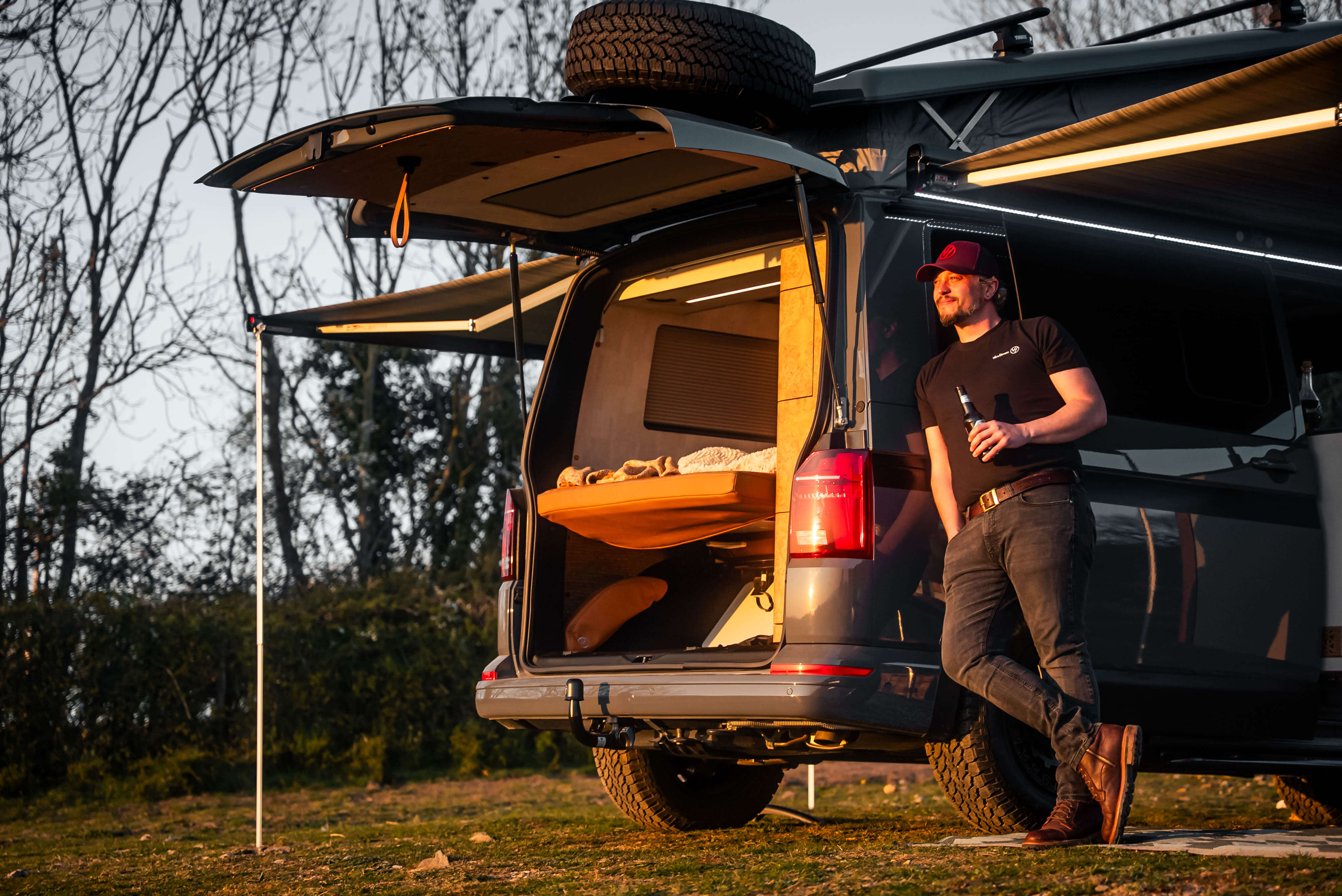 Van Haven camper at golden hour, awning extended with interior lighting and bed made up